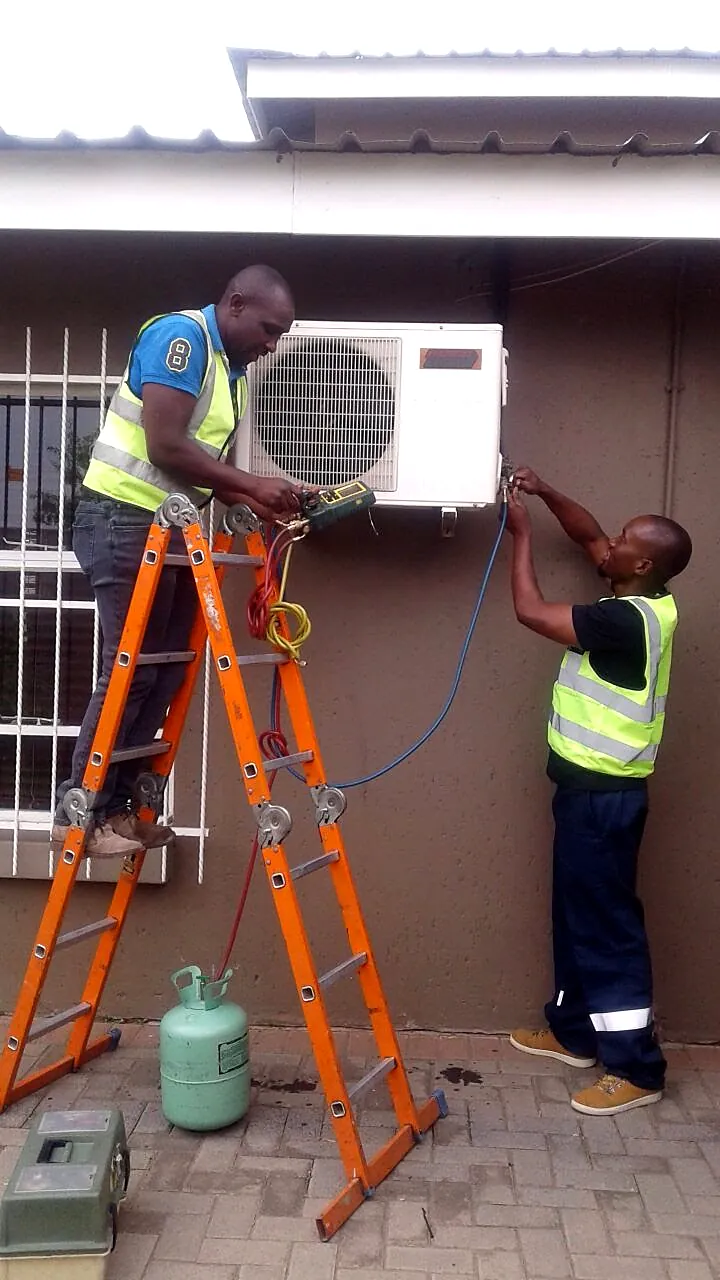 Mobile Fridge Repairs technicians on a ladder installing an aircon unit on site